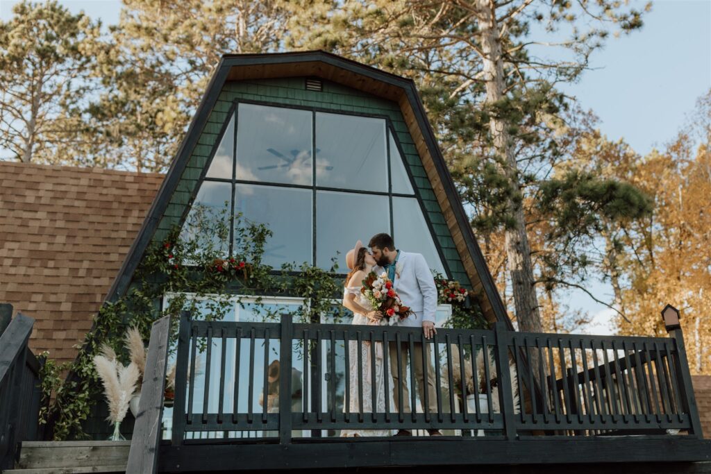 bride and groom standing on the deck of an a-frame cabin on Minnesota North Shore
