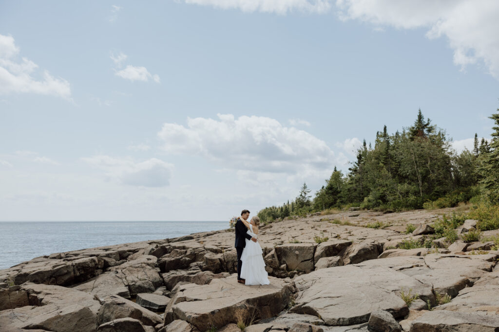 eloping couple standing on a rocky shoreline of minnesota