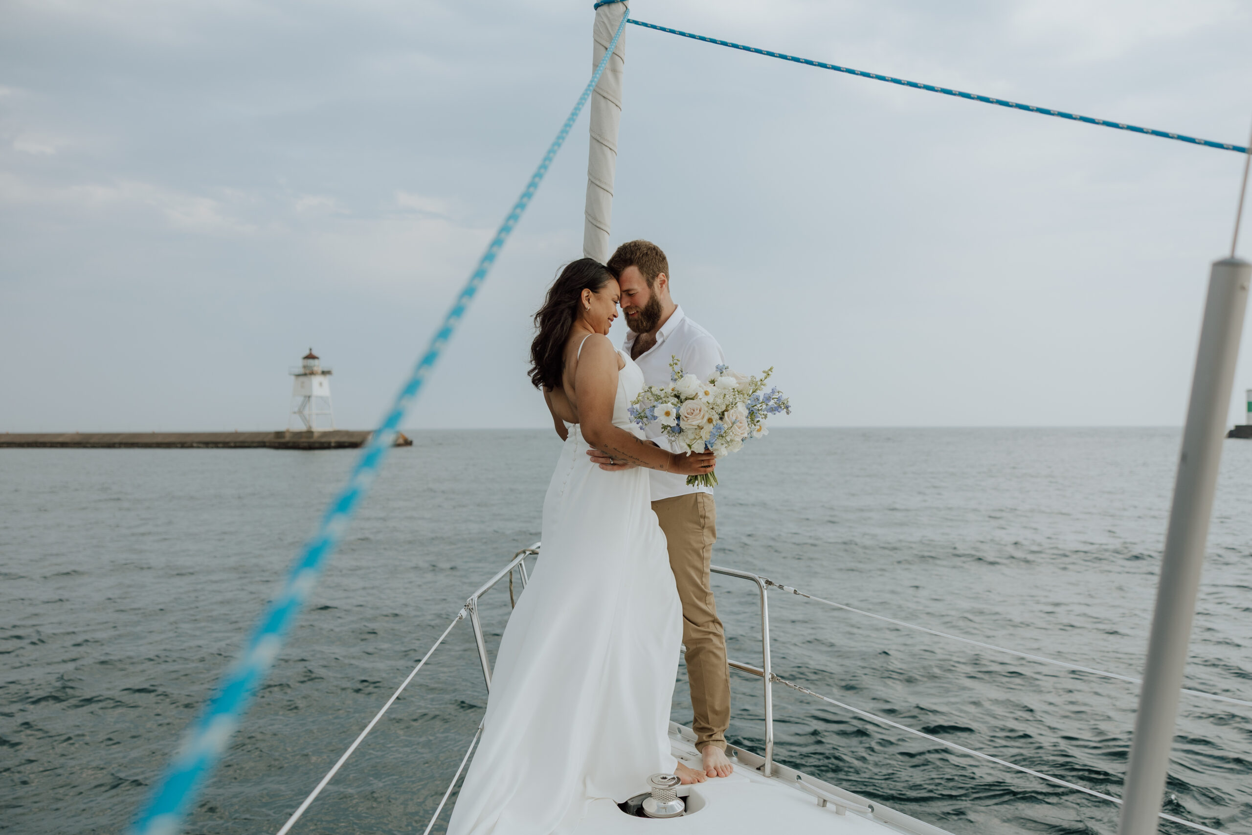 bride and groom standing on a sailboat with their foreheads together