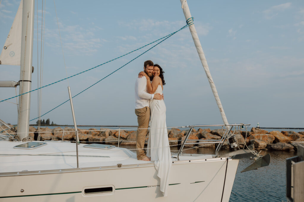bride and groom sanding on the edge of a sailboat embracing each other