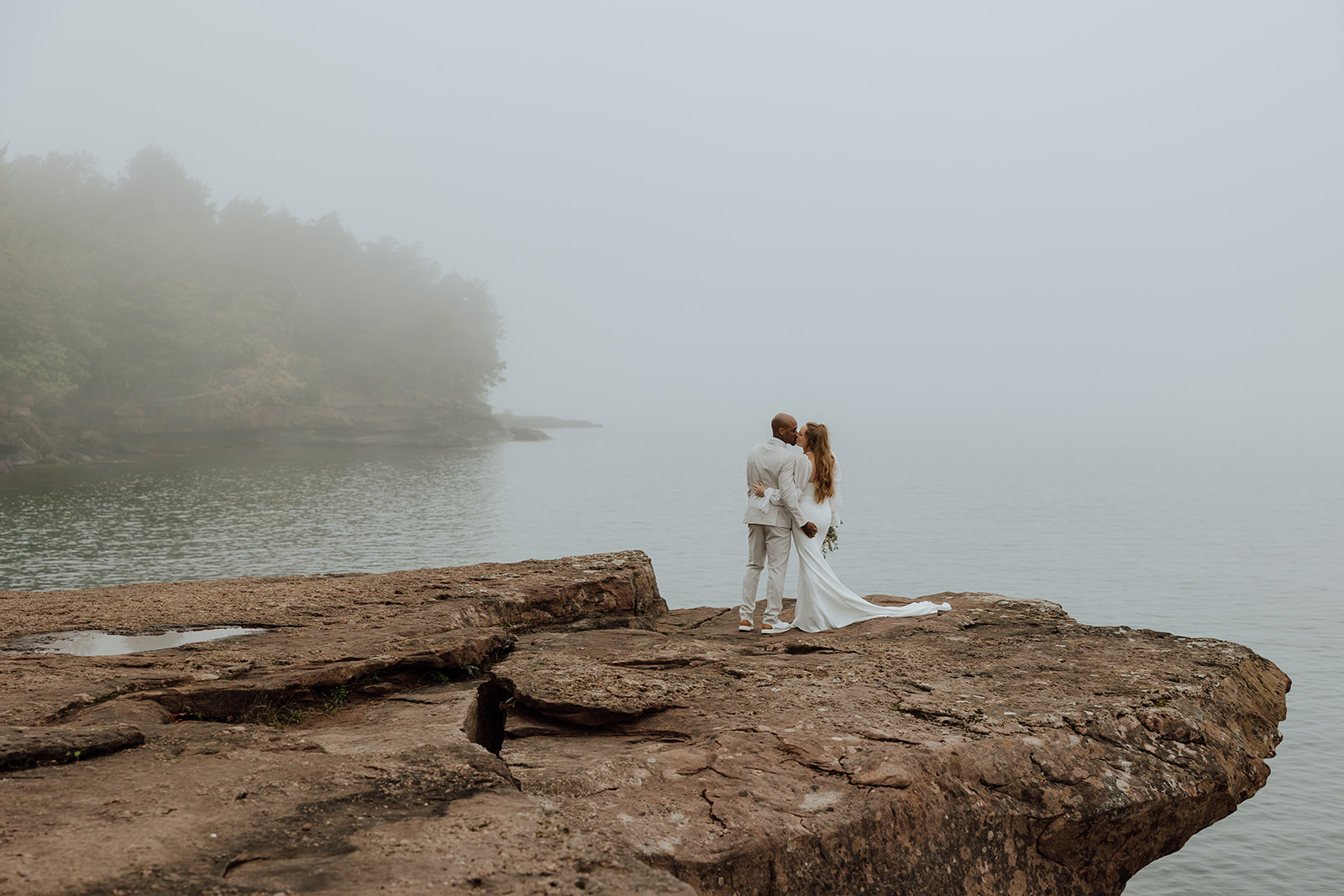 bride and groom standing on a rocky overlook on Madeline Island